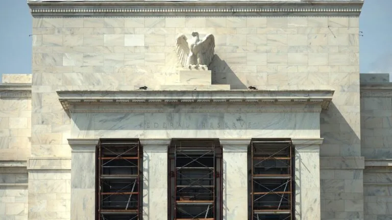 Scaffolding stands against the Federal Reserve building beneath an eagle sculpture.