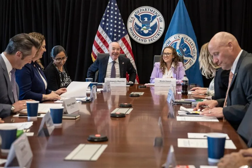 File photo: People sit around a table beneath the Department of Homeland Security seal.