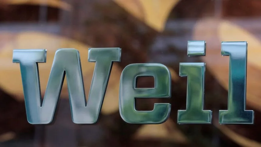 Metal letters spell Weil on a glass surface.